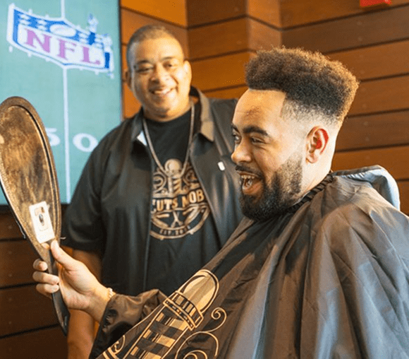 Man admiring haircut in barbershop mirror.